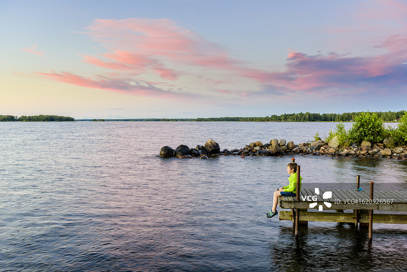 男孩在码头上看日落图片素材
