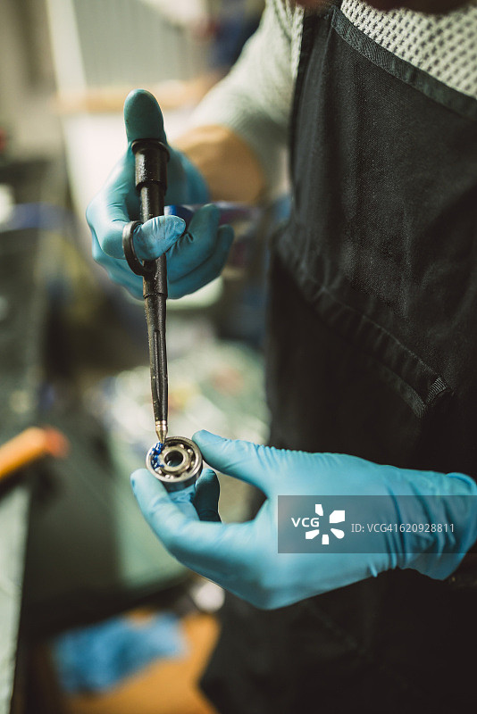 年轻的机修工润滑滚珠轴承特写图片素材