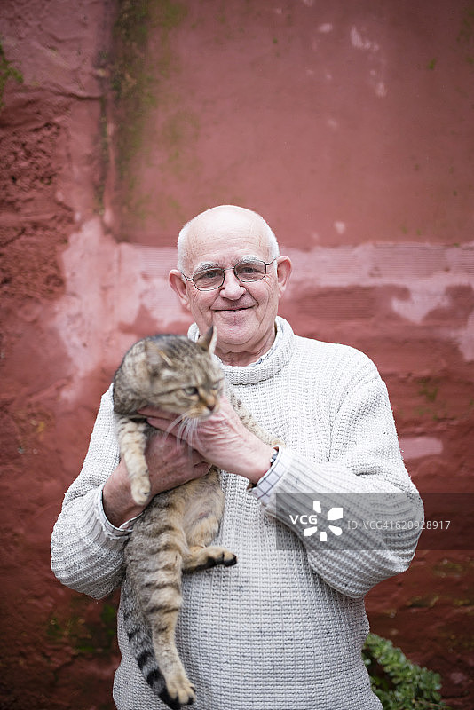 老年男人抱着虎斑猫肖像图片素材