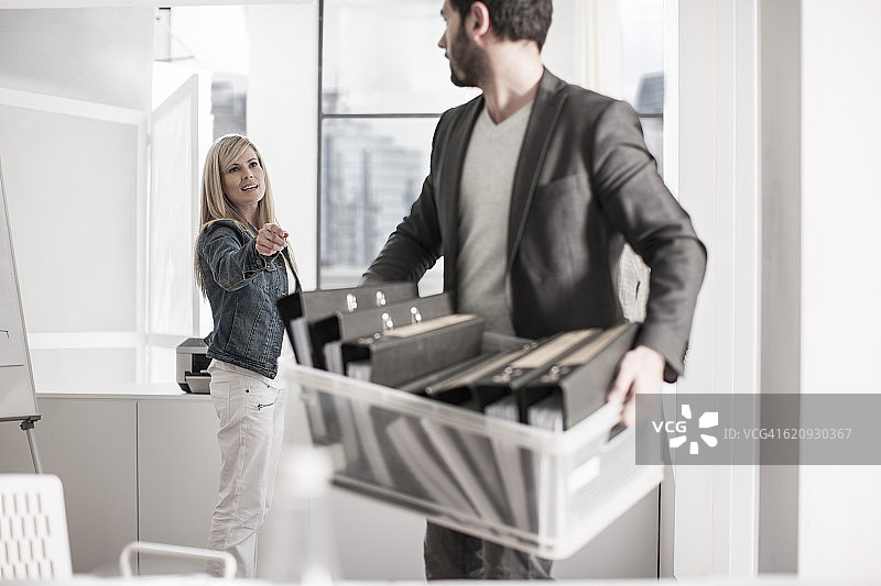 办公室里拿着文件箱与女性交谈的男人图片素材