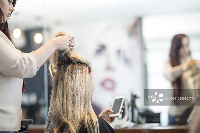 理发师在美发沙龙检查顾客的头发图片素材