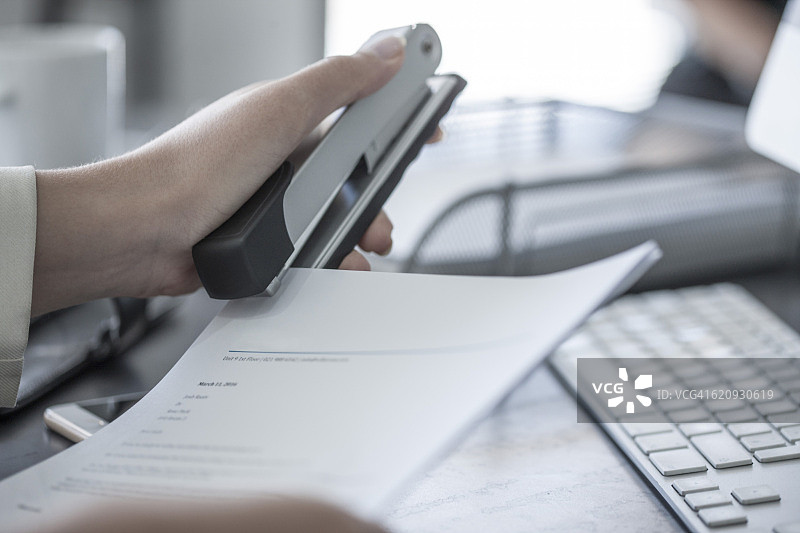 在办公桌前用订书机装订文件的女人图片素材