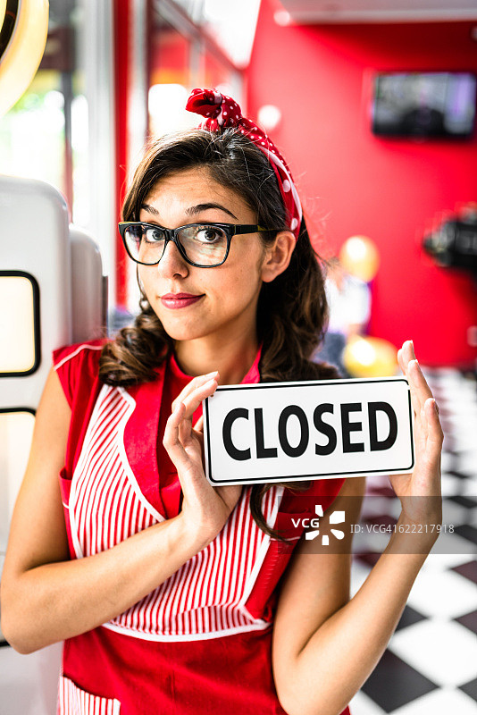 女服务员在咖啡馆的关闭标志前摆姿势图片素材
