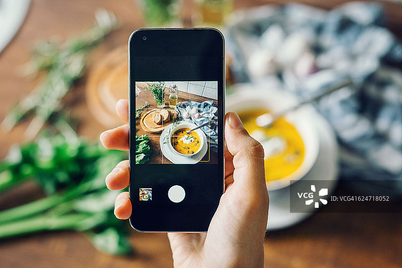 女人用智能手机拍摄南瓜汤图片素材