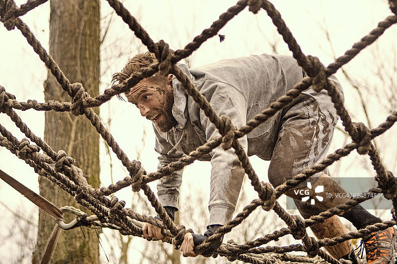 白人男子在泥泞赛跑中攀登障碍图片素材