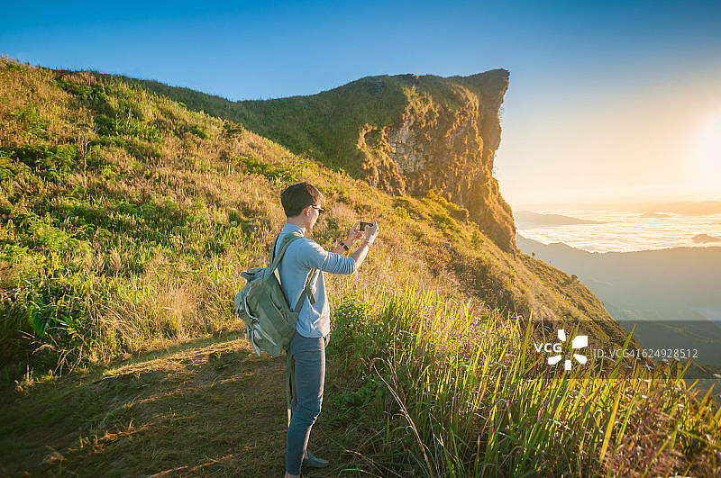 年轻旅行者站在山上欣赏日落图片素材