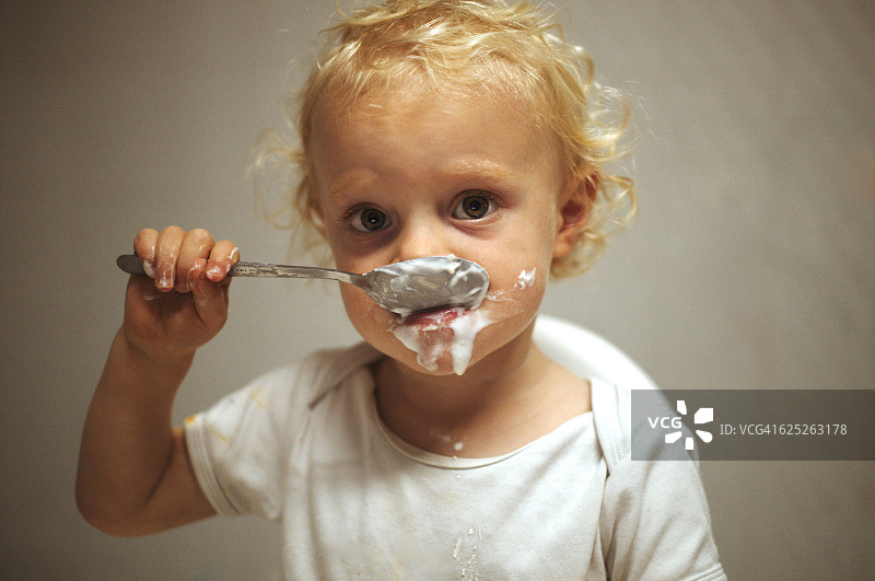 男婴坐在椅子上吃酸奶图片素材