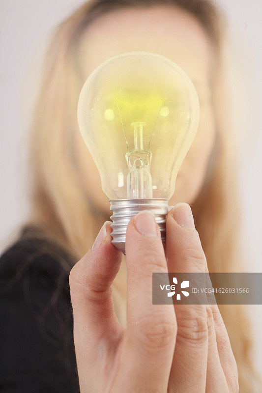 用手指握着一个发光灯泡的女人图片素材