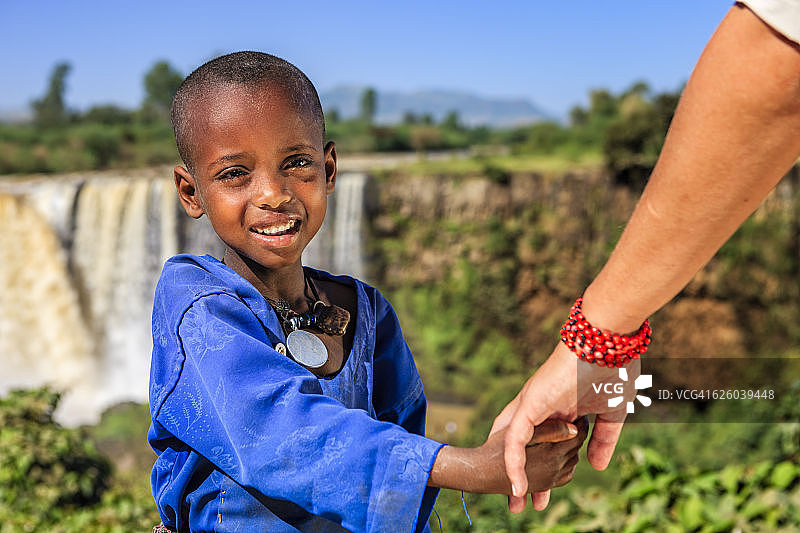 白人女性牵着非洲儿童的手图片素材