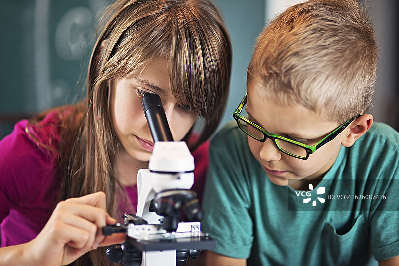 男孩和女孩在上生物课时使用显微镜图片素材