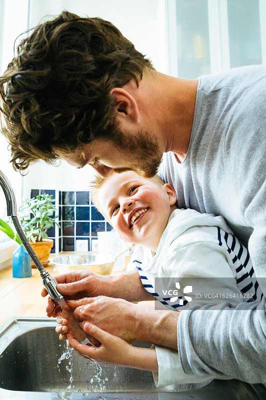 父子一起烹饪后在厨房水槽洗手图片素材