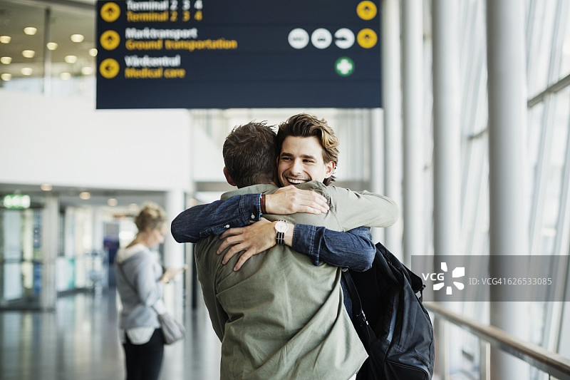 在机场拥抱男同事的快乐商人图片素材