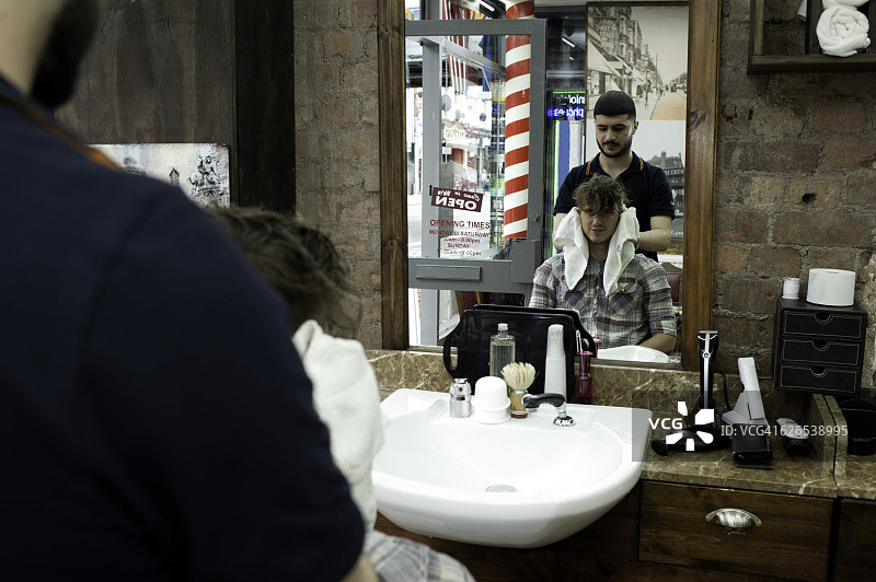 理发店里的年轻男人和理发师镜像图片素材