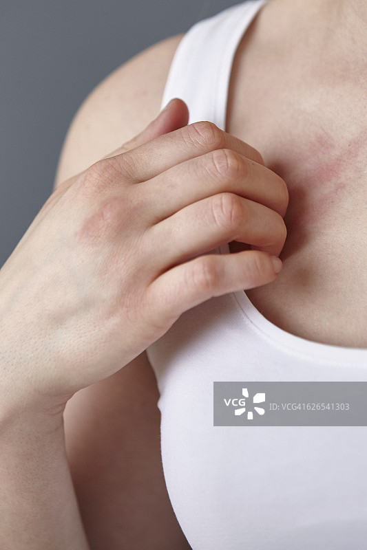 年轻女子挠胸部的特写镜头图片素材
