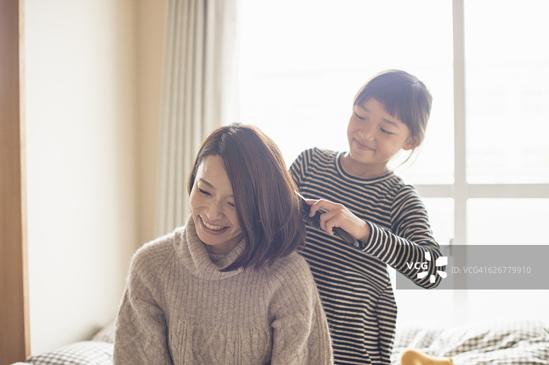 女儿在卧室为母亲梳头图片素材