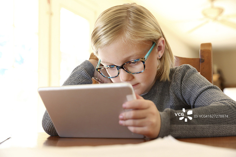 专心致志地看着她的平板电脑的年轻女孩图片素材