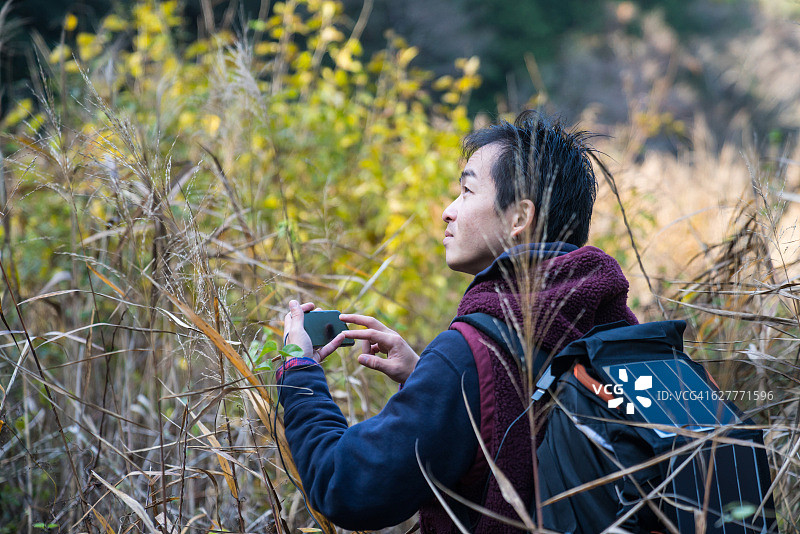 男人在荒野中使用太阳能智能手机导航图片素材