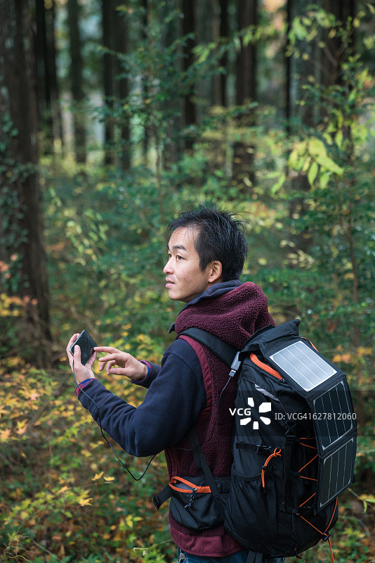 在森林中使用太阳能GPS的男人图片素材