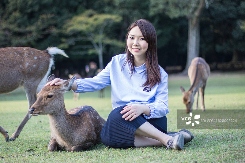 在奈良公园与鹿互动的年轻漂亮女人图片素材
