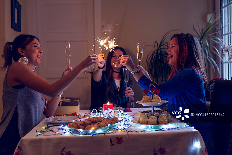 生日派对上点燃仙女棒蜡烛的三个女孩图片素材
