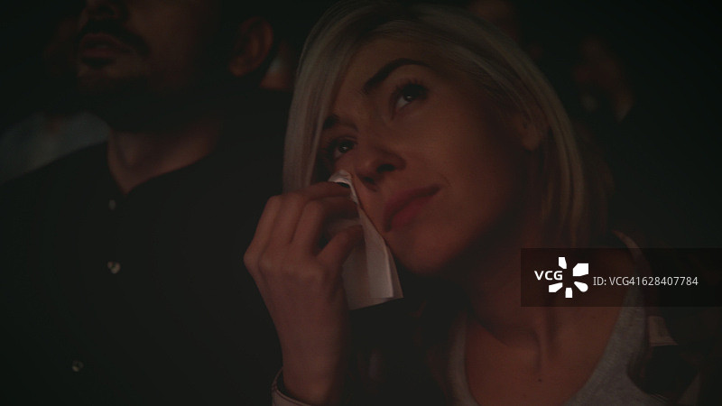 在电影院看电影时哭泣的女人图片素材