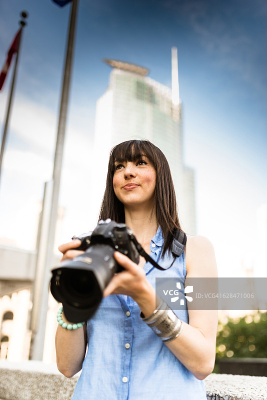 在加拿大蒙特利尔旅游的金发女游客，手持相机图片素材