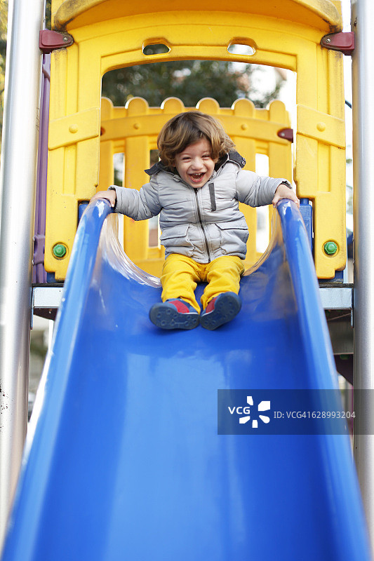 在滑梯上玩耍的快乐男婴图片素材