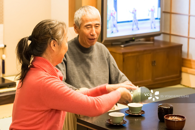 老夫妇在日式房间里自己端下午茶。图片素材