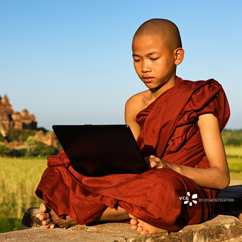 使用笔记本电脑的年轻佛教僧侣图片素材
