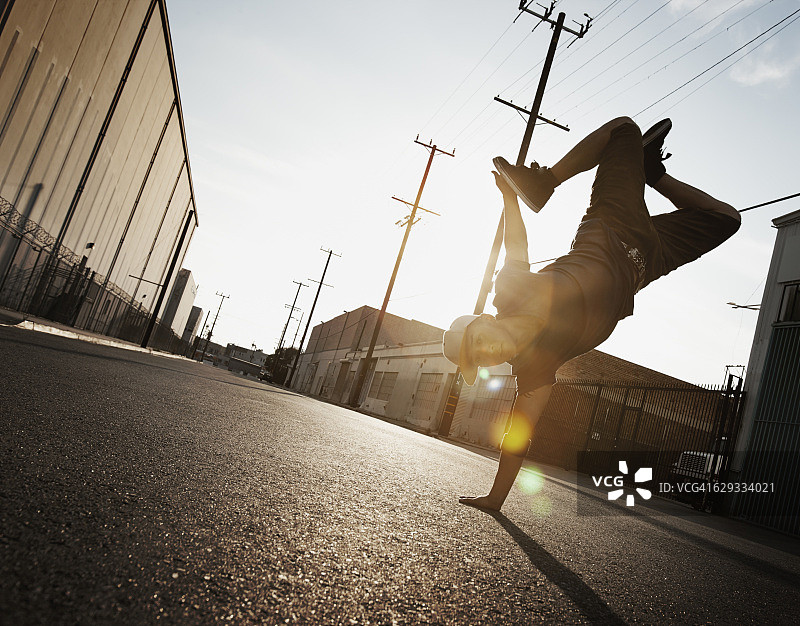 年轻男子在城市街道上跳霹雳舞，做单手倒立图片素材