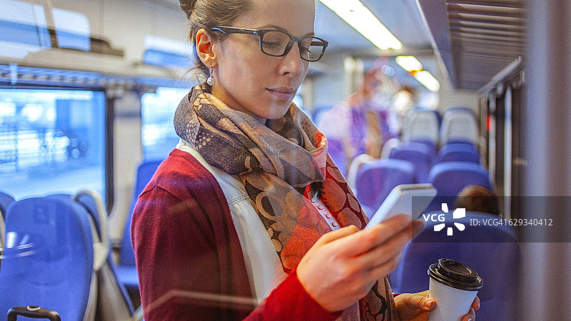 乘坐火车上下班时使用智能手机的年轻女商人图片素材