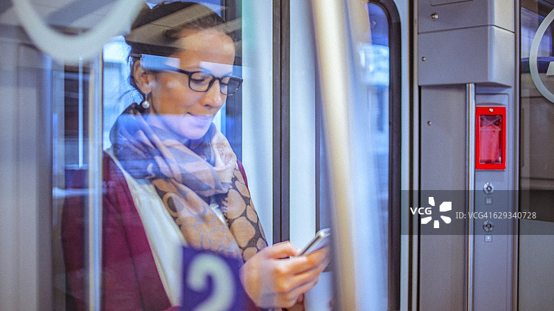 乘坐火车上下班时使用智能手机的年轻女商人图片素材
