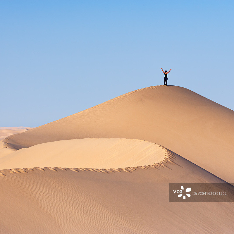 在撒哈拉沙漠沙丘顶部的女游客图片素材