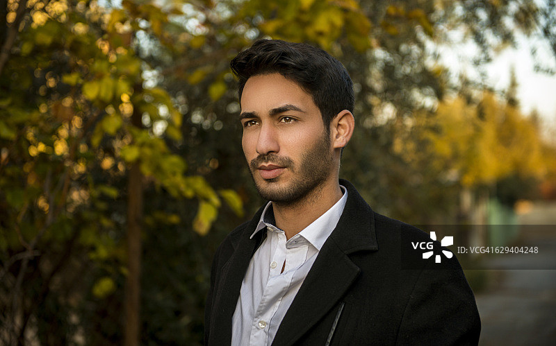 在树林中眺望远方的年轻男子肖像图片素材