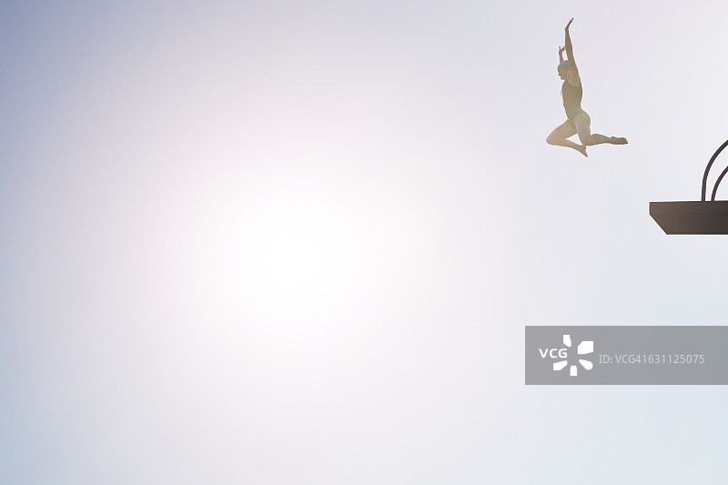 日落时分，女人从跳水台跳下图片素材