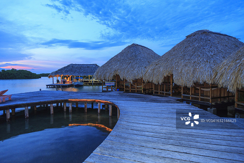 黄昏时分，男人在伯利兹圣乔治岛海滨小木屋远处图片素材