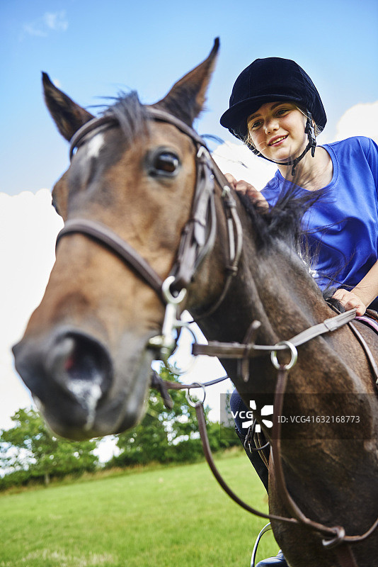 低角度仰望戴着骑马帽的骑马女孩，面带微笑图片素材