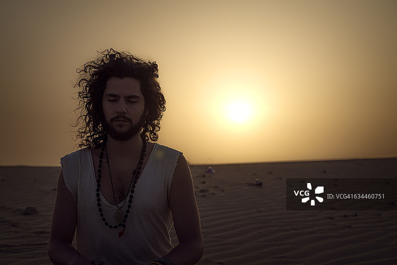 男子在沙漠中闭目冥想图片素材