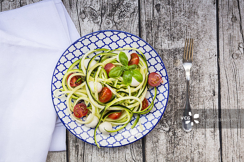 木桌上的西葫芦意面碗，配马苏里拉奶酪、樱桃番茄和罗勒图片素材