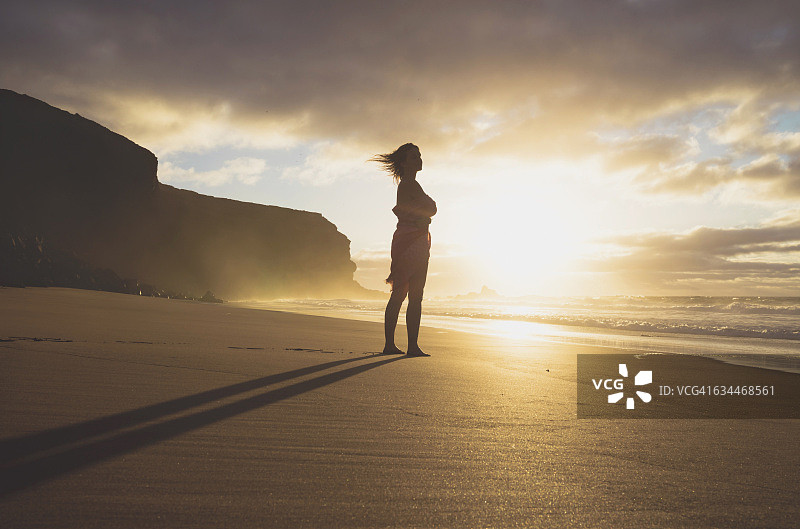 西班牙富埃特文图拉岛，日落时分站在海滩上的女人图片素材