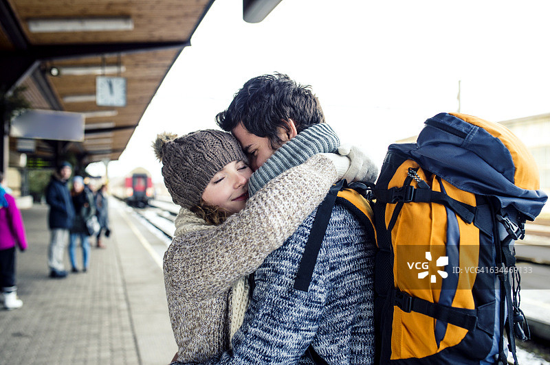 在车站站台上拥抱的微笑年轻夫妇图片素材