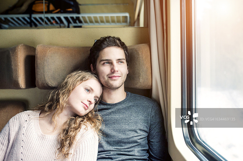 在火车车厢里看着窗外的年轻情侣图片素材