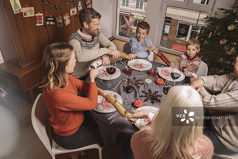 幸福的三代同堂在圣诞晚餐前拉彩炮图片素材