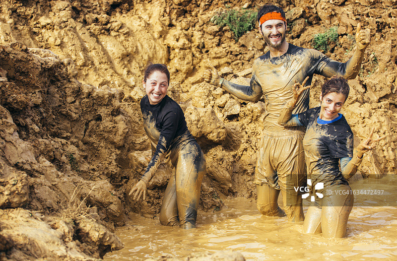 参加极限障碍赛的选手在泥地中奔跑图片素材