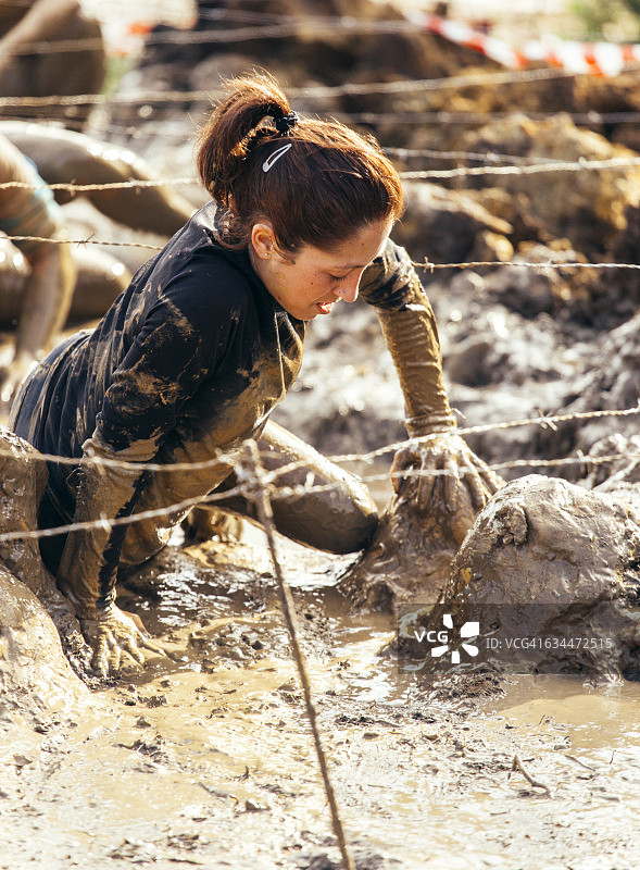 参与者在铁丝网下匍匐前进，挑战极限障碍赛图片素材