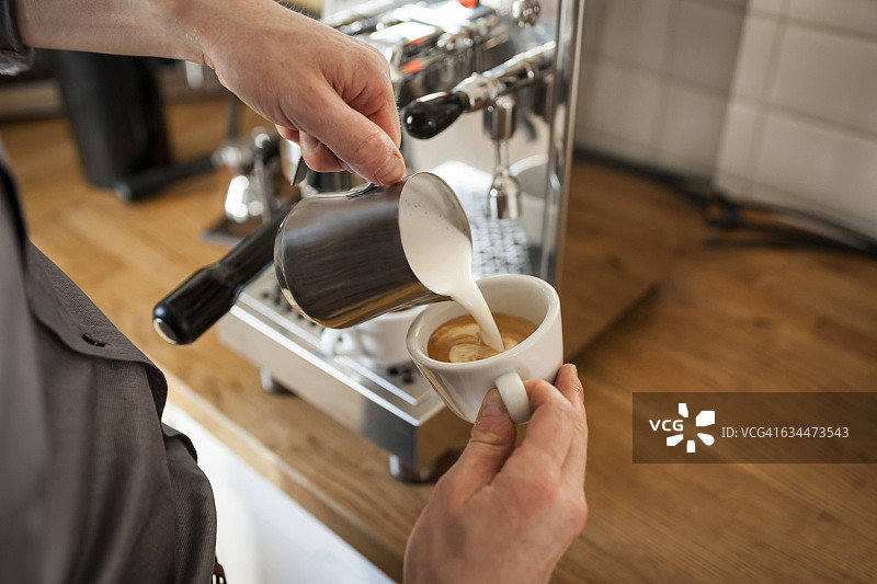 卡布奇诺，男人在咖啡杯中倒入奶泡图片素材