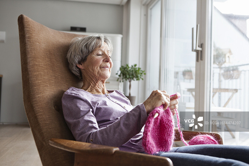 画像的年长妇女坐在扶手椅上在家编织图片素材