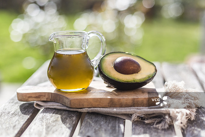 半个牛油果和木板上的牛油果油玻璃罐图片素材