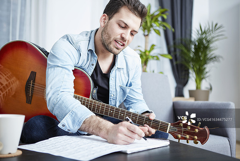 弹吉他创作歌曲的年轻男人图片素材