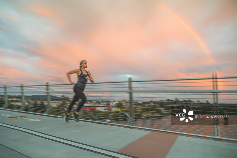 在彩虹桥上跑步的有魅力的成年女性图片素材